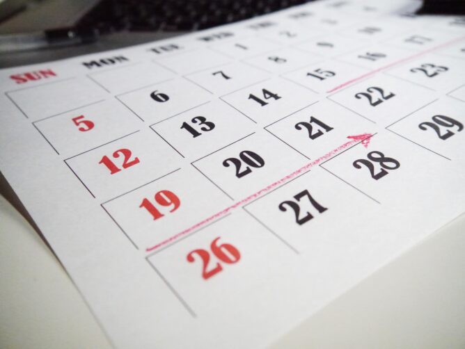 24526791_m | M Virtual(エムバーチャル) - Vライバーマネジメント事務所 Close-up of a calendar page with red Sundays (5, 12, 19, 26) and a pink diagonal line across the grid.