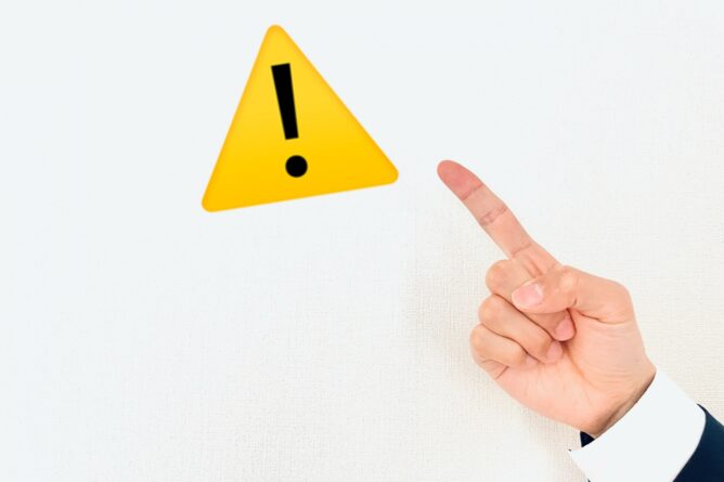 Yellow warning triangle with an exclamation mark beside a pointing finger, signaling caution