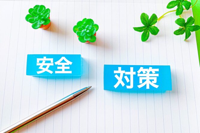 Blue signs displaying the Chinese words 安全 (Safety) and 对策 (Countermeasures) on lined paper, with a silver pen and small potted succulents nearby.
