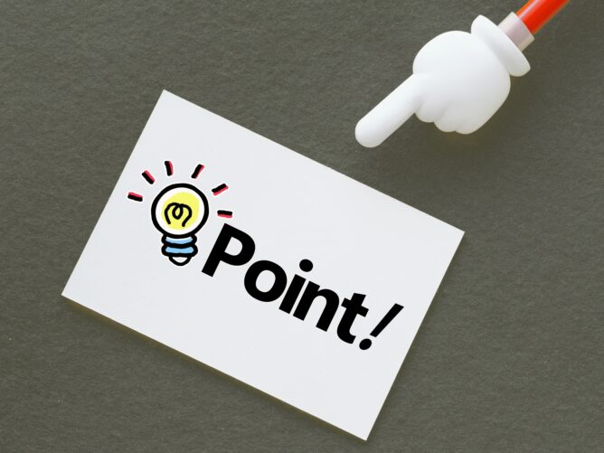 Card with a drawn light bulb and the word'Point' being pointed at by a white cartoon hand on a dark background.
