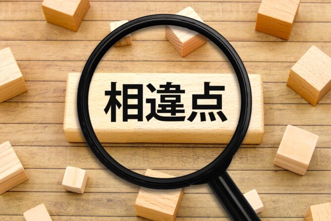 Magnifying glass over a wooden tile with the Japanese word 相違点 (differences) written on it.