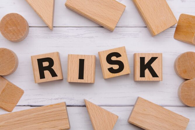 Wooden letter blocks spell 'RISK' on a white wooden surface, suggesting risk or risk management concepts.