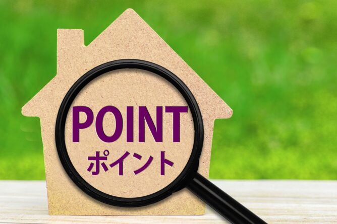 Cardboard house shape with a large magnifying glass over the word POINT in purple and Japanese text, implying home loan points.