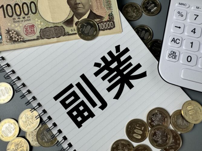 Japanese 10,000 yen banknote with coins scattered on a notebook showing the word 請求 (invoice) beside a calculator.