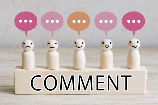 34587227_m | M Virtual(エムバーチャル) - Vライバーマネジメント事務所 Five small wooden figures with colorful speech bubbles above them, placed behind a block labeled COMMENT, symbolizing discussion and feedback.