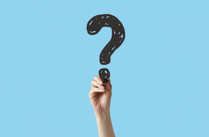 Raised hand holding a large black question mark against a light blue background.