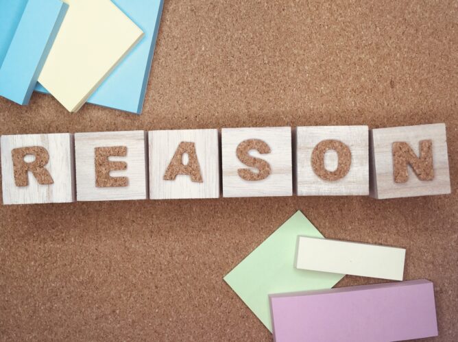 Wooden letter blocks spell 'REASON' on a corkboard, surrounded by pastel sticky notes and papers.
