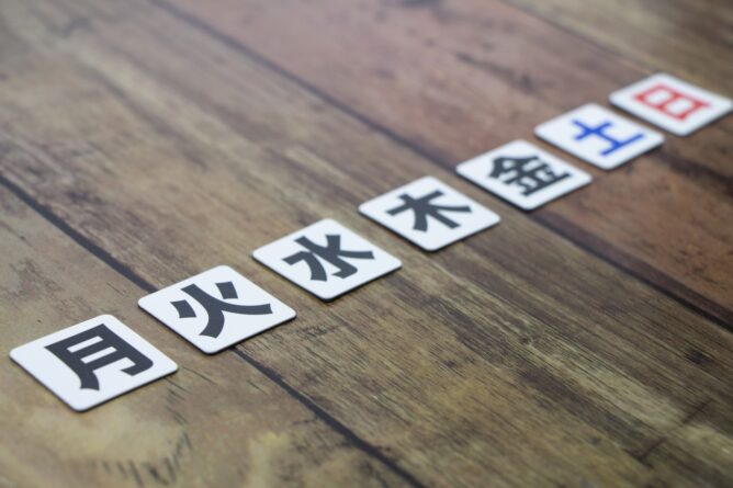 4186521_m | M Virtual(エムバーチャル) - Vライバーマネジメント事務所 Row of Mahjong tiles on a wooden table displaying the Chinese characters for moon, fire, water, wood, metal, earth.
