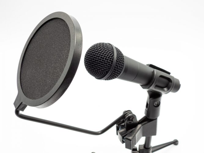 Close-up of a black microphone with a round pop filter on a stand, ready for recording.