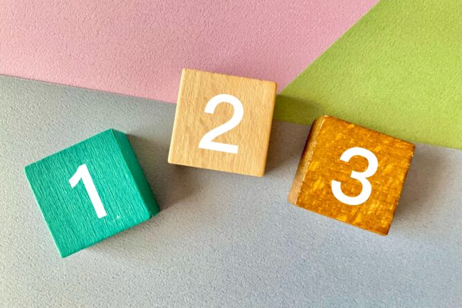 23110435_m | M Virtual(エムバーチャル) - Vライバーマネジメント事務所 Three colorful wooden number blocks 1, 2, and 3 on pastel surfaces (pink, gray, green).i