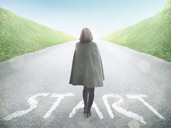 28987003_m | M Virtual(エムバーチャル) - Vライバーマネジメント事務所 Person in a coat walks toward a bright light on a road with 'START' painted on the pavement, symbolizing beginning a journey.