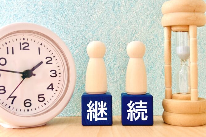 32795095_m | M Virtual(エムバーチャル) - Vライバーマネジメント事務所 Clock on the left with two wooden peg dolls and blue blocks bearing white kanji characters, and an hourglass on the right.