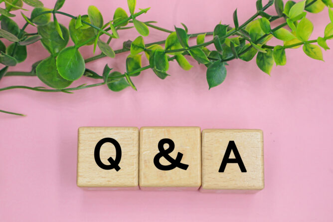 33800865_m | M Virtual(エムバーチャル) - Vライバーマネジメント事務所 Wooden blocks spell 'Q & A' on a pink surface with trailing green vines above.