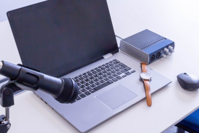 4018515_m | M Virtual(エムバーチャル) - Vライバーマネジメント事務所 Laptop on a desk with a large microphone on a stand and an audio interface nearby, set for recording or podcasting.